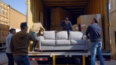 Four men loading a couch into a semi trailer.